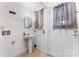 Small bathroom featuring sink, mirror, towel rack, window with curtains, and a door at 2255 Milton Rd, Charlotte, NC 28215