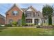 Charming brick home featuring manicured landscaping, lush green lawn, and a welcoming front porch at 2812 Julian Glen Cir, Waxhaw, NC 28173