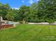 Expansive backyard with lush lawn, mature trees, inground pool, and tiki bar; perfect for outdoor enjoyment at 3038 Sterling Ct, Fort Mill, SC 29707