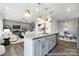 Open concept kitchen island transitions to a dining area featuring white walls, wood-look floors and modern pendant lighting at 32562-B Millingport Rd # 7155, New London, NC 28127