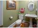 A charming powder room features stylish fixtures, including an oval mirror and a pedestal sink, plus colorful accessories at 3504 High Ridge Rd, Charlotte, NC 29270