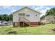 View of the rear exterior featuring a staircase, brick foundation, and a well-maintained lawn at 380 Woodlawn Ave, Cramerton, NC 28032