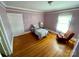 Cozy bedroom featuring hardwood floors, soft lilac walls, and natural light from a window at 380 Woodlawn Ave, Cramerton, NC 28032