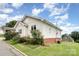 Side exterior of home with white siding, well-maintained lawn, and brick foundation at 380 Woodlawn Ave, Cramerton, NC 28032