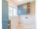 Functional laundry room with blue cabinets, a window for natural light, and connections for a washer and dryer at 3921 Bon Rea Dr, Charlotte, NC 28226
