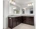 This bathroom includes double sinks with granite countertops, tile floors, dark cabinets and large, framed mirrors with vanity lighting at 4013 Hamilton Mill Dr, Waxhaw, NC 28173