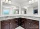 This bathroom includes double sinks with granite countertops, tile floors, dark cabinets and large, framed mirrors with vanity lighting at 4013 Hamilton Mill Dr, Waxhaw, NC 28173