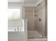 This tiled walk-in shower with glass doors features neutral tiles, a mounted shower head, and tiled shampoo storage at 4013 Hamilton Mill Dr, Waxhaw, NC 28173