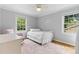 Bright bedroom with hardwood floors, two windows, a white bed frame, and a comfortable pink chair at 4024 Tyndale Ave, Charlotte, NC 28210