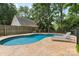 A kidney-shaped pool is surrounded by a decorative concrete patio and chairs, enclosed by a backyard privacy fence at 4024 Tyndale Ave, Charlotte, NC 28210