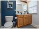 Bathroom features a vanity with wood cabinets, a toilet, and a dark blue accent wall at 4075 Clover Nw Rd, Concord, NC 28027