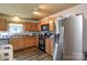 Bright kitchen boasts stainless steel refrigerator, wood cabinets, and a window view at 4075 Clover Nw Rd, Concord, NC 28027