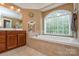 Bright bathroom with a soaking tub beneath a large arched window at 5004 Woodview Ln, Matthews, NC 28104
