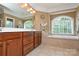 Elegant bathroom with a soaking tub, dual sinks, and natural light at 5004 Woodview Ln, Matthews, NC 28104