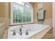 Close-up on a bathtub with chrome hardware under a sunlit window at 5004 Woodview Ln, Matthews, NC 28104