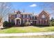 Stately brick home featuring dormer windows, mature landscaping, and a well-manicured lawn at 5004 Woodview Ln, Matthews, NC 28104
