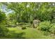 Serene backyard featuring a greenhouse, raised garden beds, and a beautifully maintained lawn area at 504 S Hayne St, Monroe, NC 28112