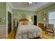 Cozy bedroom featuring hardwood floors, neutral green walls, and a large white bed with decorative pillows at 504 S Hayne St, Monroe, NC 28112