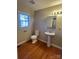 Cozy bathroom featuring wood-look floors, pedestal sink, and a classic comfort-height toilet at 524 Railroad Nw Dr, Concord, NC 28025