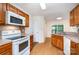Modern kitchen with wooden cabinetry, white appliances, and a view to the backyard through the window at 5625 Linda Vista Ln, Charlotte, NC 28216