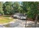Charming white cottage with pergola and a spacious gravel driveway surrounded by lush greenery and a fenced yard at 800 Woodlawn St, Belmont, NC 28012
