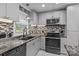 Updated kitchen with stainless steel appliances, granite countertops, tile backsplash, and gray cabinets at 800 Woodlawn St, Belmont, NC 28012