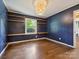 Bedroom features a unique wood-paneled wall with built-in shelving, hardwood floors, and a modern light fixture at 827 Fairbanks Rd, Charlotte, NC 28210