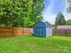 A backyard shed provides ample storage space, complemented by a privacy fence and verdant lawn at 827 Fairbanks Rd, Charlotte, NC 28210