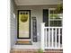 Up-close, the front door and porch feature welcome decor and black shutters at 835 Jet St, Kannapolis, NC 28081