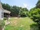 Green backyard featuring a covered patio, fire pit area, mature trees, and grass at 8605 Soaring Eagle Ln, Waxhaw, NC 28173