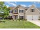 Two-story home featuring beige siding, an arched window, two-car garage, and an American flag displayed on the front porch at 9593 Indian Beech Nw Ave, Concord, NC 28027