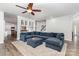 Spacious living room featuring a large blue sectional sofa, ceiling fan, hardwood floors, and staircase at 9593 Indian Beech Nw Ave, Concord, NC 28027