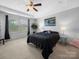 Primary bedroom with neutral colors, a ceiling fan, a large window and a bridge painting at 10426 Kempsford Dr, Charlotte, NC 28262