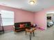 This bonus room features light pink walls, a futon, and a stylish coffee table at 10426 Kempsford Dr, Charlotte, NC 28262