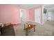 This bonus room features light pink walls, a futon, and a stylish coffee table at 10426 Kempsford Dr, Charlotte, NC 28262