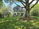 White home with porch, complemented by a large shade tree and a sprawling green lawn at 1051 14Th Avenue Nw Dr, Hickory, NC 28601