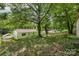 View of the backyard showing the mature trees with canopy, fencing and white storage building at 1075 Parkview Dr, Gastonia, NC 28054