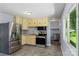 Functional kitchen features stainless steel appliances, yellow cabinets, and durable tile floors at 1075 Parkview Dr, Gastonia, NC 28054