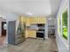 Functional kitchen features stainless steel appliances, yellow cabinets, and durable tile floors at 1075 Parkview Dr, Gastonia, NC 28054