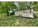Backyard shed surrounded by mature trees and landscaping, door and window with view of back yard at 1075 Parkview Dr, Gastonia, NC 28054