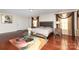 This spacious bedroom features dark wood floors, tray ceilings, and elegant, natural light-filtering window treatments at 12822 Plumleaf Dr, Charlotte, NC 28213
