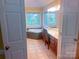 Bright bathroom with a jetted tub, tiled floors, and vanity seating, offering comfort and functionality at 15494 Donnington Dr, Charlotte, NC 28277