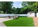 Serene backyard with lush green turf, enclosed by a white fence, featuring a cozy fire pit and storage shed at 2412 Chesterfield Ave, Charlotte, NC 28205