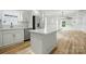 Open kitchen area with an island, stainless appliances, white cabinets, and wood flooring at 251 Hall Nw Ave, Concord, NC 28027