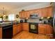 The kitchen has wood cabinets, stainless steel appliances, and black countertops, and is illuminated by natural light at 2598 Old Ashworth Nw Ln, Concord, NC 28027