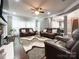 Spacious living room with hardwood floors, comfortable leather seating, lots of windows, and modern ceiling fan at 2652 Bedford Nw Pl, Concord, NC 28027