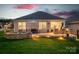 A cozy backyard featuring a stone patio, fire pit, and grill, illuminated by warm outdoor lighting at 5058 Antebellum Dr, Iron Station, NC 28080