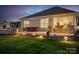 A cozy backyard featuring a stone patio, fire pit, and grill, illuminated by warm outdoor lighting at 5058 Antebellum Dr, Iron Station, NC 28080