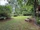 Lush backyard featuring a stone table and benches, surrounded by mature trees and landscaping at 5198 Wright Dr, Hickory, NC 28602