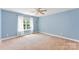 A bedroom with light blue walls, carpeted floors, a window and white curtains, offering natural light at 6300 Latta Springs Cir, Huntersville, NC 28078